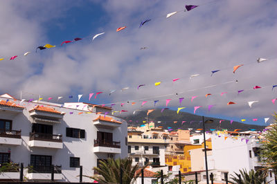 Multi colored flags hanging against sky in city