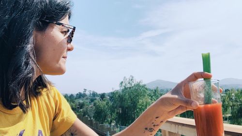 Close-up portrait of woman holding glass against mountain