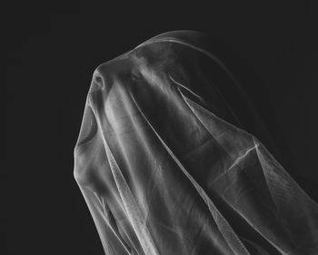 Side view of woman with textile screaming against black background
