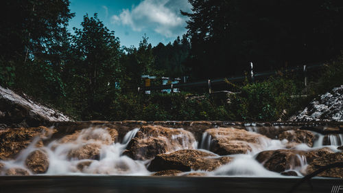 Scenic view of waterfall in forest against sky