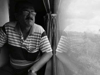 Man looking away through window while sitting in train