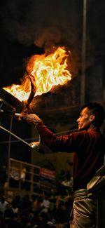 Man holding burning fire at night