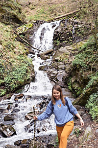 Full length of young woman standing by waterfall