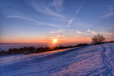 Scenic view of snow covered field against sky at sunset