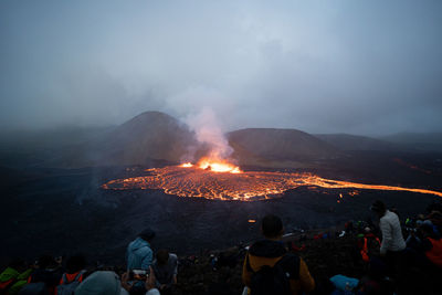 Group of people on snowcapped mountain against sky during sunset