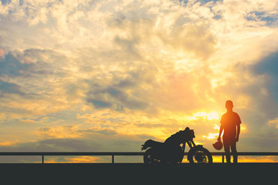 Silhouette people riding horse against sky during sunset