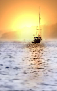 Boat sailing on sea against sky during sunset
