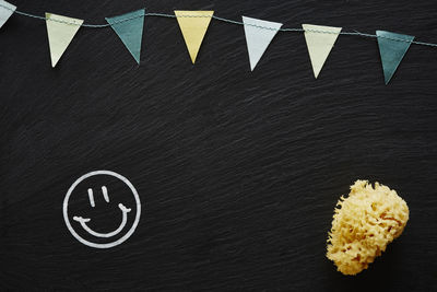 Colorful bunting by sponge and smiley face on blackboard