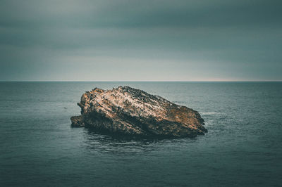 Rock formation in sea against sky