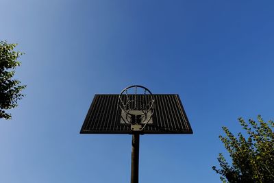 Directly below shot of basketball hoop against clear blue sky on sunny day