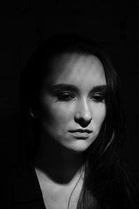Close-up portrait of beautiful young woman over black background
