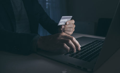 Midsection of man using laptop on table