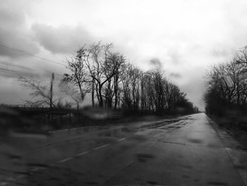 Road amidst bare trees against sky