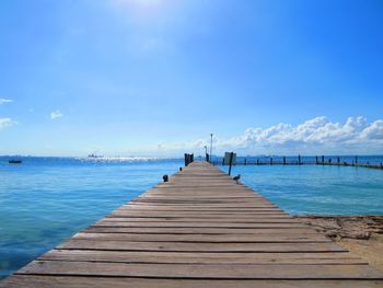 Pier over sea against blue sky