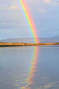 Scenic view of rainbow over lake against sky