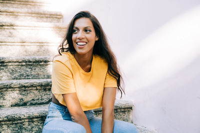 Portrait of smiling young woman sitting on staircase