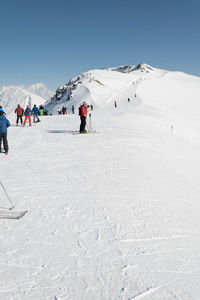 People skiing on snowcapped mountain against sky