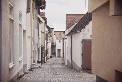 Walkway amidst buildings against sky