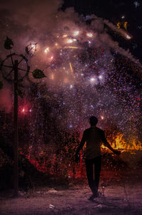 Rear view of man looking at firework display at night