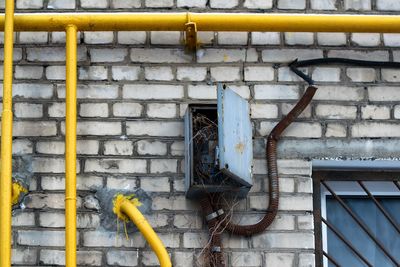 Yellow pipes and meter board on brick wall