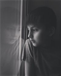 Portrait of boy looking through window at home