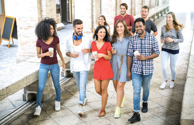 High angle view of happy friends walking on footpath in city