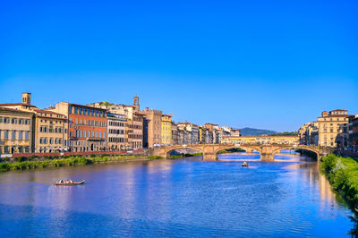 Arch bridge over river against buildings in city