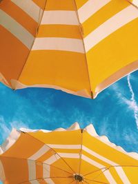 Low angle view of yellow parasols against sky