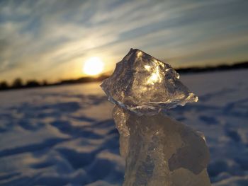 Close-up of frozen rock on land against sky during sunset