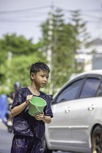 Full length of boy standing on car against trees