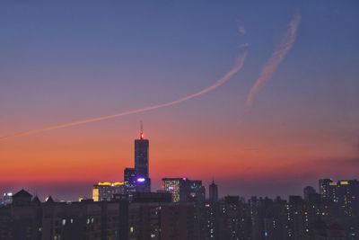 Illuminated buildings against sky during sunset