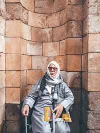 Portrait of man standing against brick wall