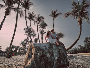 Couple sitting on rock against trees