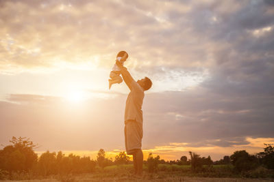 Man standing on field against sky during sunset