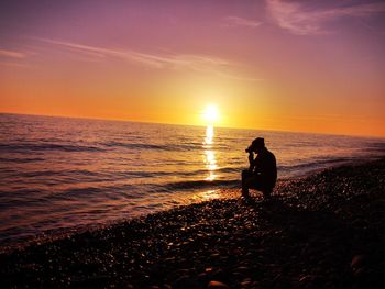 Silhouette people on beach against sky during sunset