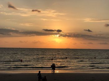 Silhouette people on beach against sky during sunset