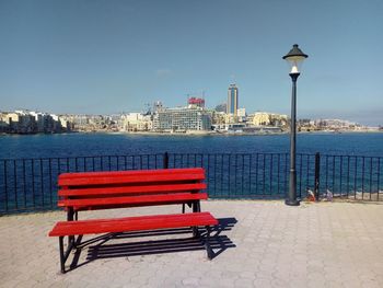 Empty bench by street against buildings in city