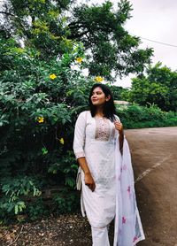 Young woman standing against plants