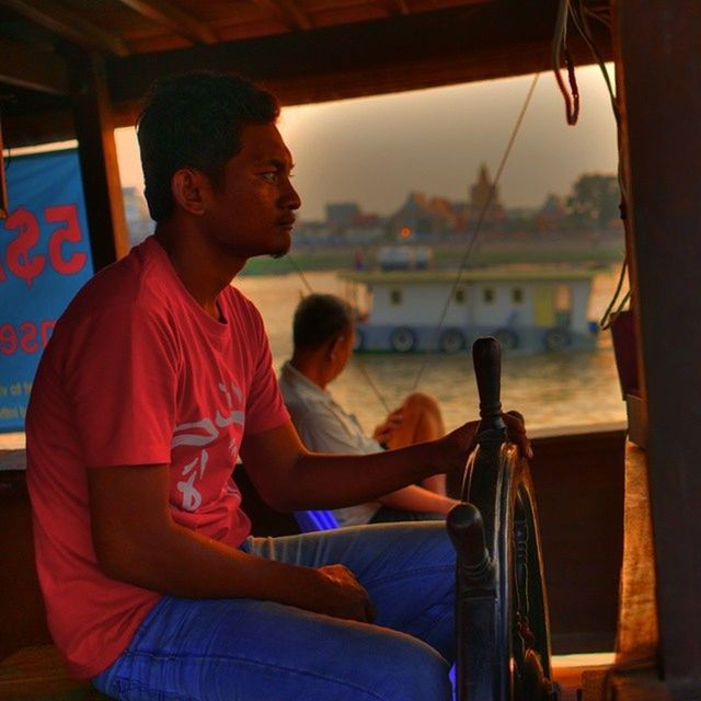 lifestyles, person, sitting, casual clothing, leisure activity, young adult, young men, three quarter length, indoors, transportation, chair, water, side view, nautical vessel, smiling, waist up, mode of transport