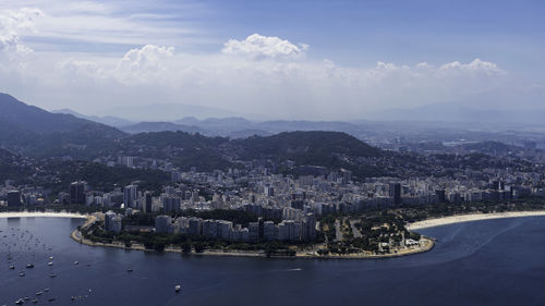 High angle view of city by sea against sky