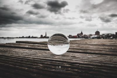 Close-up of crystal ball by buildings against sky