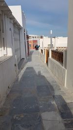 Footpath amidst buildings against sky