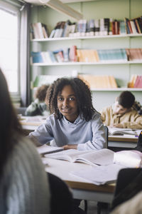 Girl with books sitting at desk in classroom