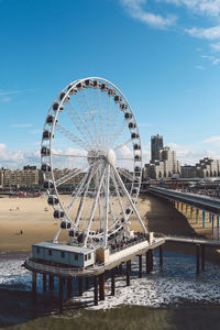 Ferris wheel by river against sky