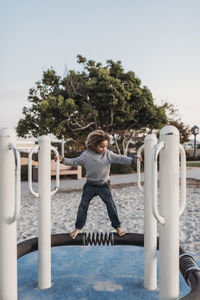 Young school aged boy standing on park structure playing at dusk