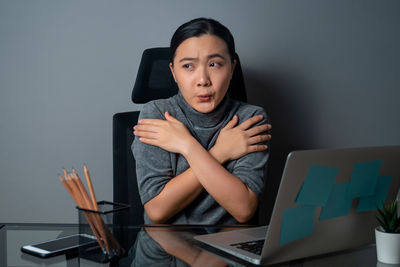 Portrait of young woman using mobile phone while sitting on table