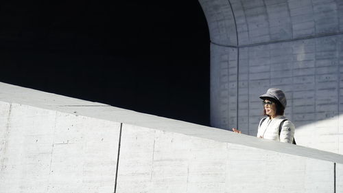 Side view of woman looking away against wall