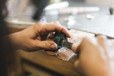 Cropped hands of female artisan shaping equipment on table in workshop