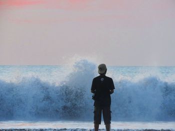 Rear view of man looking at sea against sky