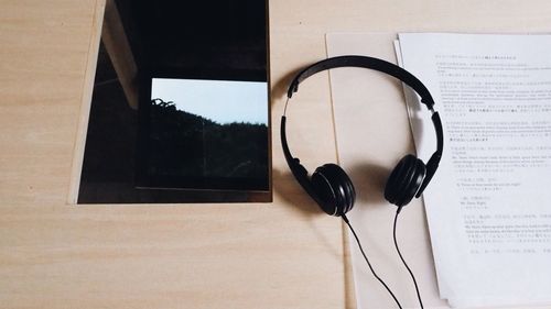 High angle view of headphones by papers and mirror on table